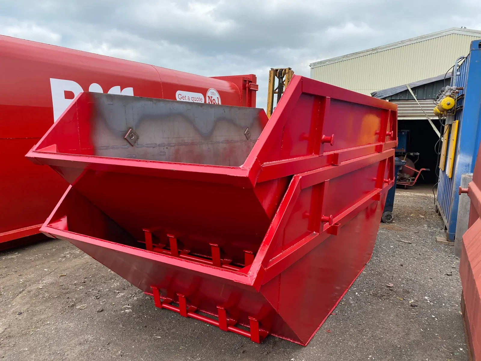 A freshly painted red builders' skip in the yard