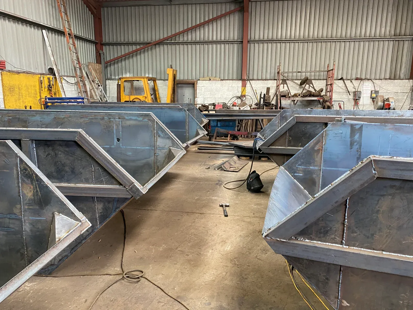 Bare steel skips under construction in the workshop, before painting