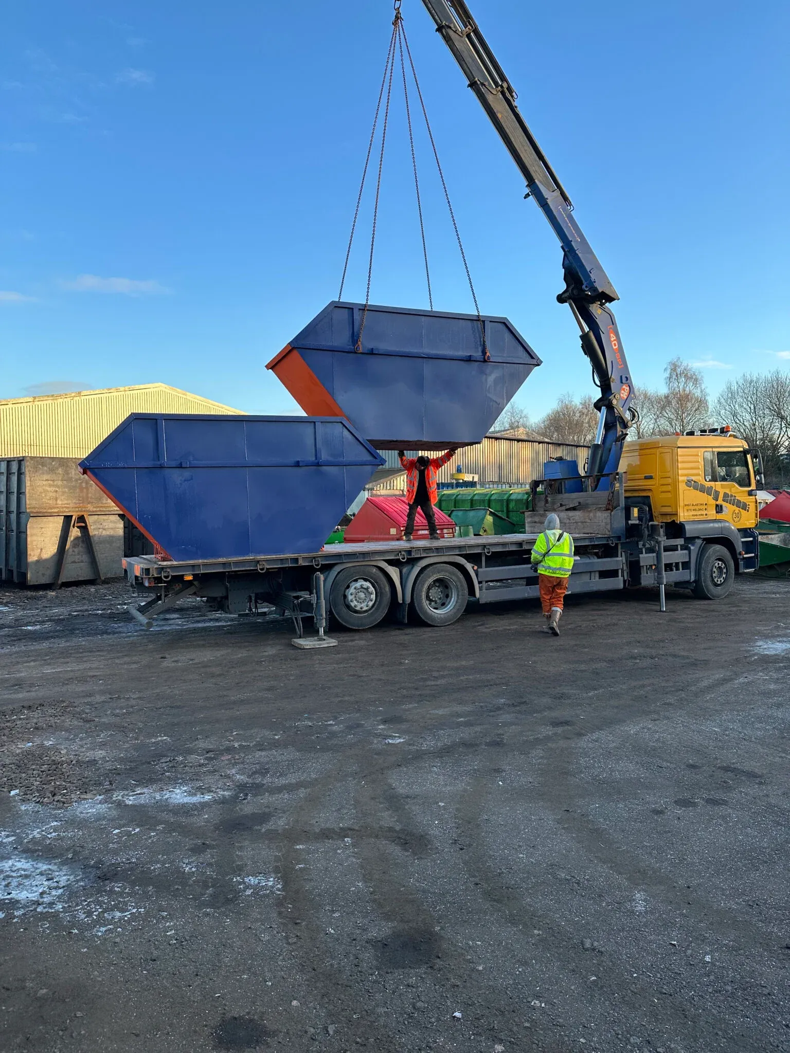 A skip lorry lifting a part-exchange skip on delivery